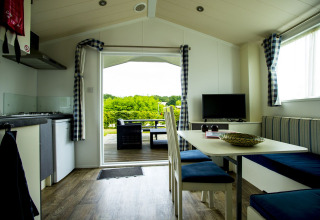 Interior view of Delta Lodge at Holiday Park Duinhoeve, Netherlands, overlooking deck and greenery outside.