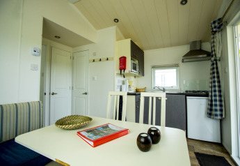 Binnenzicht van Delta Lodge op Holiday Park Duinhoeve, Nederland, met eettafel en kitchenette.