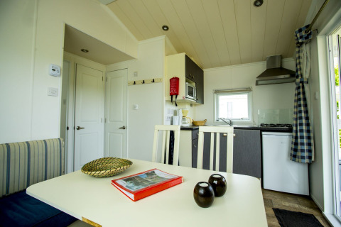 Moderne indretning af Delta Lodge på Holiday Park Duinhoeve, Nederlandene, med spisebord og tekøkken.