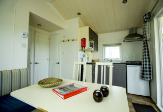 Moderne indretning af Delta Lodge på Holiday Park Duinhoeve, Nederlandene, med spisebord og tekøkken.