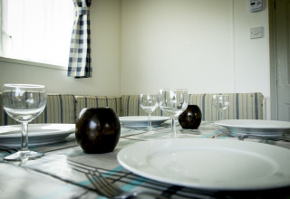 Gedekte eettafel met wijnglazen, borden en kaarsen in Delta Lodge van Holiday Park Duinhoeve, Nederland.