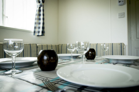 Gedekte eettafel met wijnglazen, borden en kaarsen in Delta Lodge van Holiday Park Duinhoeve, Nederland.