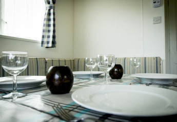 Mesa de comedor puesta con copas de vino, platos y velas en Delta Lodge del Holiday Park Duinhoeve, Países Bajos.
