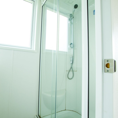Cabine de douche moderne avec portes vitrées et fenêtres au Delta Lodge au Holiday Park Duinhoeve, Pays-Bas.