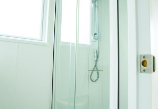 Modern shower cabin with glass doors and windows at Delta Lodge in Holiday Park Duinhoeve, Netherlands.