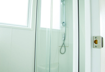 Cabina de ducha moderna con puertas de vidrio y ventanas en Delta Lodge de Holiday Park Duinhoeve, Países Bajos.