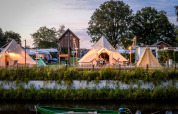 Tienda tipi Happy Harbor con baño en Holiday Park Mölke, Países Bajos, con luces nocturnas acogedoras.