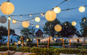 Evening view of Happy Harbor tent and bathroom at Holiday Park Mölke, Netherlands, with lantern lights.
