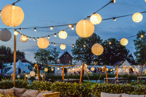 Evening view of Happy Harbor tent and bathroom at Holiday Park Mölke, Netherlands, with lantern lights.