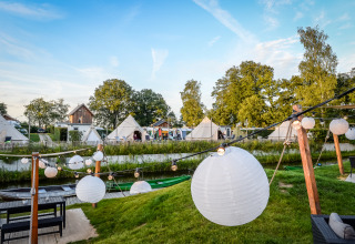 Vue sur des tipis et des lanternes décoratives près de la tente Happy harbor avec salle de bain au Holiday Park Mölke, Pays-Bas.