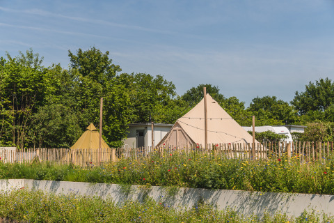 Tente tipi avec salle de bain au Holiday Park Mölke, Pays-Bas, entourée de fleurs et verdure.