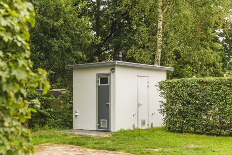 Modern buitenbadkamer bij Happy Harbor tent in Holiday Park Mölke, omgeven door groene natuur.