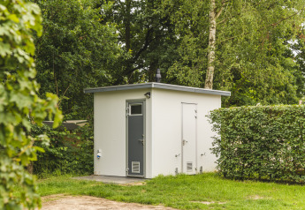 Modern buitenbadkamer bij Happy Harbor tent in Holiday Park Mölke, omgeven door groene natuur.