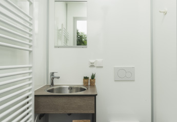Modern compact badkamer in een tipi-tent met spiegel, wastafel, toilet, handdoeken en een servicepakket.
