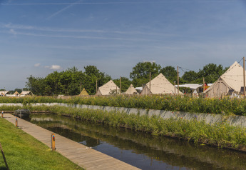 Uitzicht op Happy Harbor tipi-tenten met badkamer bij Vakantiepark Mölke, Nederland, langs een kanaal.