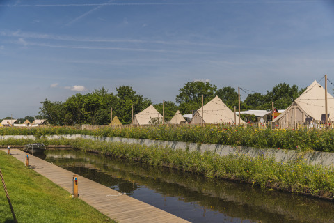 View of Happy Harbor teepee tents with bathrooms at Holiday Park Mölke, Netherlands, beside a canal.