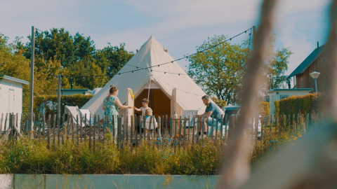Familie vor dem Happy harbor Zelt mit Bad im Holiday Park Mölke, Niederlande, bei sonnigem Wetter.
