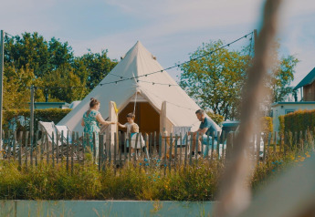 Familie vor dem Happy harbor Zelt mit Bad im Holiday Park Mölke, Niederlande, bei sonnigem Wetter.