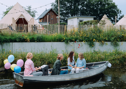Vier mensen varen in een boot met ballonnen voor tipi tenten bij Holiday Park Mölke in Nederland.