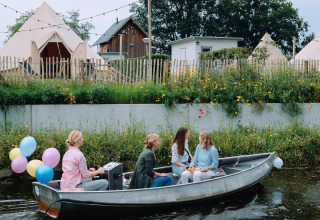 Fire personer sejler i en båd med balloner foran tipitelte ved Holiday Park Mölke i Nederlandene.