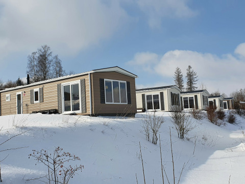 Cabañas Chalet Brilon cubiertas de nieve en Camping & Ferienpark Brilon, Alemania, con paisaje invernal.