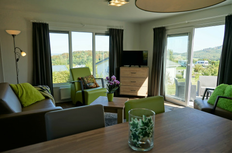 Sala luminosa en Chalet Brilon, Camping & Ferienpark Brilon, Alemania, con detalles verdes y vistas.