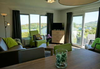 Sala luminosa en Chalet Brilon, Camping & Ferienpark Brilon, Alemania, con detalles verdes y vistas.