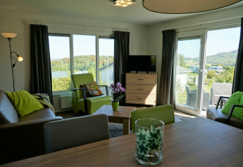 Sala luminosa en Chalet Brilon, Camping & Ferienpark Brilon, Alemania, con detalles verdes y vistas.