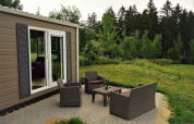 Terras van Chalet Brilon met tuinmeubelen, gazon en bos bij Camping & Ferienpark Brilon in Duitsland.