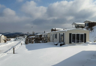 Cabañas cubiertas de nieve en Chalet Brilon, Camping & Ferienpark Brilon, Alemania, con cielo nublado.