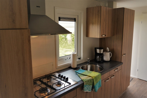 Cocina moderna en Chalet Brilon con estufa de gas, fregadero, cafetera y gabinetes de madera en Ferienpark Brilon.