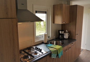 Cocina moderna en Chalet Brilon con estufa de gas, fregadero, cafetera y gabinetes de madera en Ferienpark Brilon.