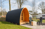 Trekkerspod-Lodge im Kampeerdorp de Zandstuve, Niederlande, mit gewölbter Hütte und Sitzgelegenheiten.