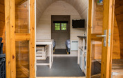 Innenraum einer Trekkerspod-Lodge im Kampeerdorp de Zandstuve, Niederlande, mit Betten und TV.