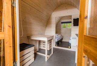 Vista interior de la Trekkerspod lodge en Kampeerdorp de Zandstuve, Países Bajos, con paredes de madera y decoración sencilla.