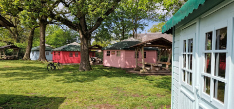 Foto von kleinen, bunten Hütten unter Bäumen im Writers Hut bei Zomerlicht, Niederlande.