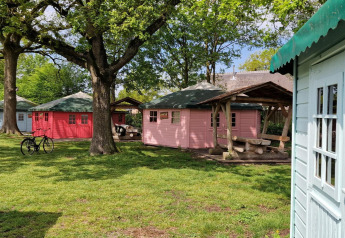 Photo de petites cabanes colorées sous de grands arbres au Writers Hut, Zomerlicht, Pays-Bas.