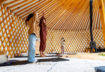 Mennesker laver yoga i et luksuriøst glampingtelt med hyggelig indretning og varmt træinteriør.