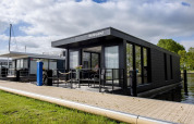 Casa flotante moderna 'De Waterparel' en Welcome In - Friesland, Países Bajos, atracada junto al muelle.
