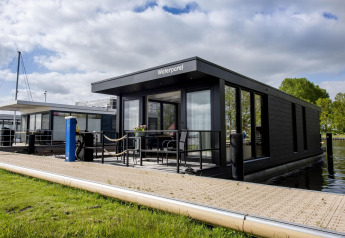 Casa flotante moderna 'De Waterparel' en Welcome In - Friesland, Países Bajos, atracada junto al muelle.