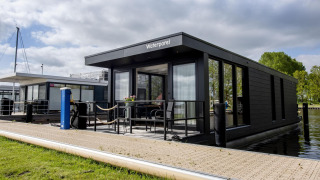 Péniche moderne 'De Waterparel' à Welcome In - Friesland, Pays-Bas, amarrée au bord de l'eau.