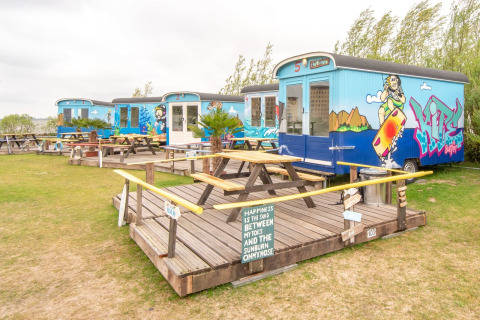Casas pequeñas Tiny wagon en Marina Parcs Almere, Países Bajos, con arte de graffiti y bancos de picnic.