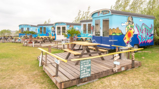 Casas pequeñas Tiny wagon en Marina Parcs Almere, Países Bajos, con arte de graffiti y bancos de picnic.