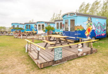 Casas pequeñas Tiny wagon en Marina Parcs Almere, Países Bajos, con arte de graffiti y bancos de picnic.