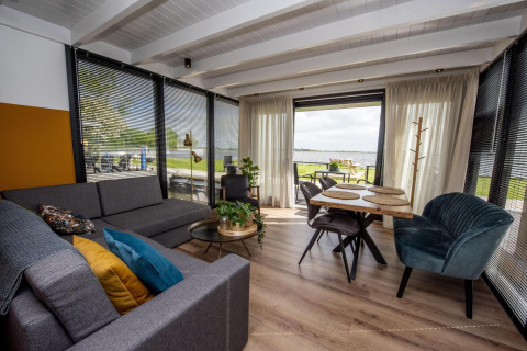 Salón y comedor moderno en la casa flotante 'De Waterparel', Friesland, Países Bajos, con vistas al agua.