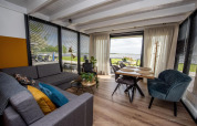 Salón y comedor moderno en la casa flotante 'De Waterparel', Friesland, Países Bajos, con vistas al agua.
