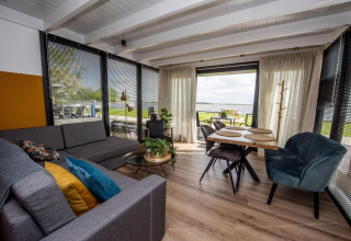 Salón y comedor moderno en la casa flotante 'De Waterparel', Friesland, Países Bajos, con vistas al agua.