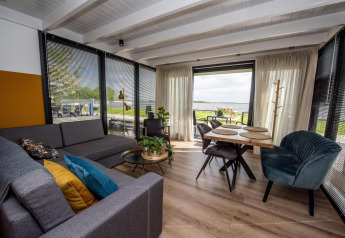 Modernes Wohnzimmer und Essbereich auf dem Hausboot 'De Waterparel' in Friesland mit Seeblick.