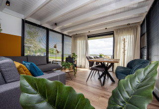 Zona de estar moderna en la casa flotante 'De Waterparel' con vistas y decoración elegante en Friesland, Países Bajos.