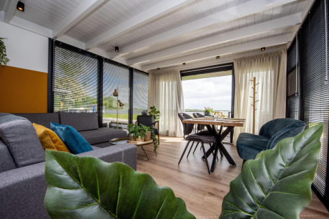 Salon moderne sur houseboat 'De Waterparel', grandes fenêtres et décoration élégante à Friesland, Pays-Bas.
